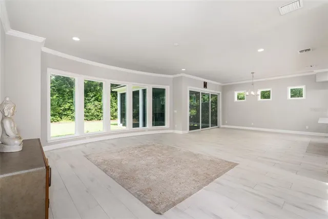a view of an empty room with a window and chandelier