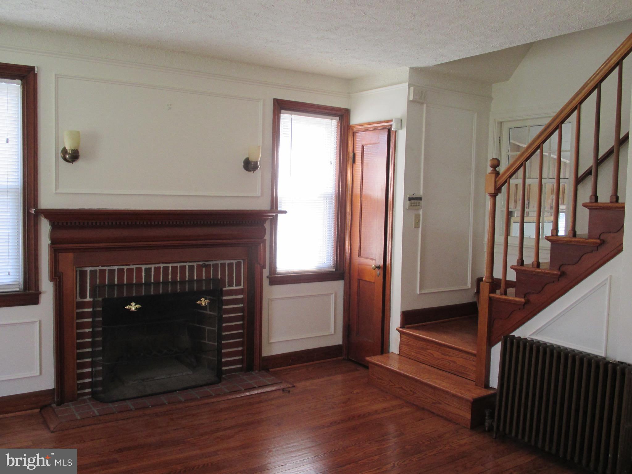 716 Dorchester Road Baltimore, MD 21229 - Photo 9 of 20 a view of an empty room with wooden floor fireplace and a window