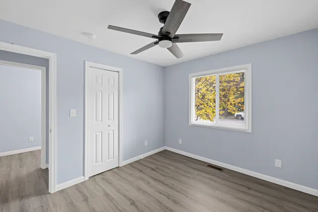 an empty room with wooden floor and windows