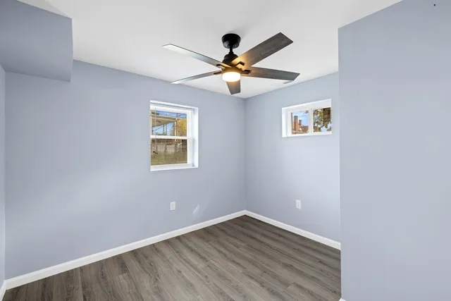 a view of empty room with wooden floor and fan