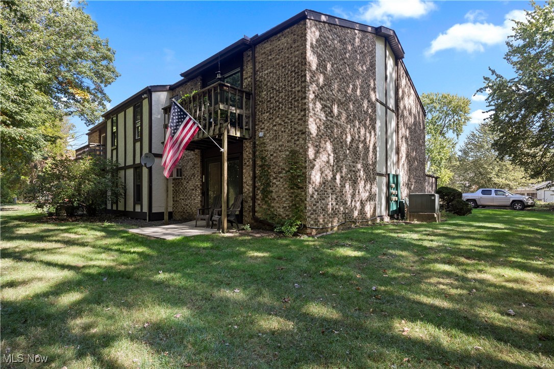 29379 Detroit Road Westlake, OH 44145 - Photo 21 of 23 View of side of property featuring brick siding, a lawn, a patio area, and a balcony