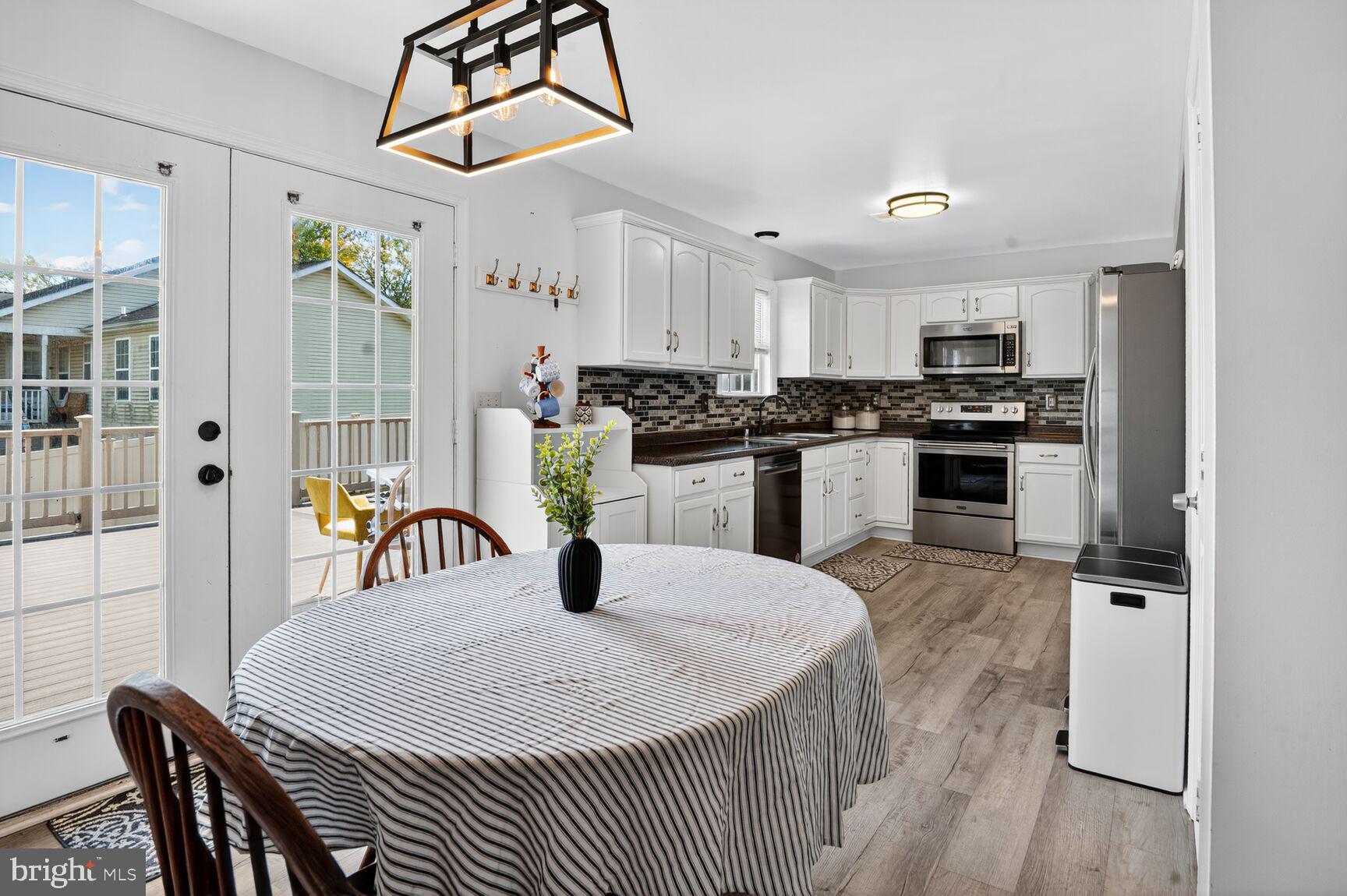71 Fairground Avenue Taneytown, MD 21787 - Photo 6 of 36 a kitchen with stainless steel appliances granite countertop a stove a refrigerator a dining table and chairs with wooden floor