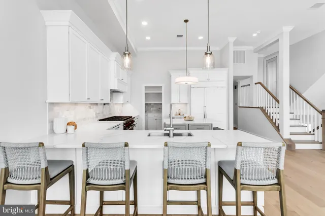 a kitchen with stainless steel appliances kitchen island granite countertop a dining table chairs and white cabinets