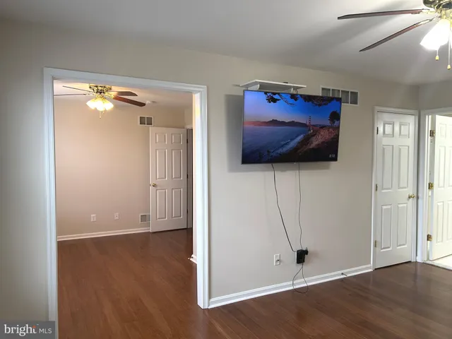 an empty room with wooden floor fan and windows