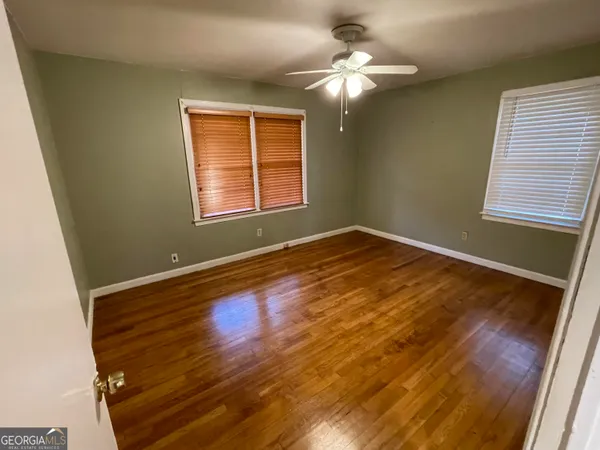 a view of an empty room with wooden floor and a window