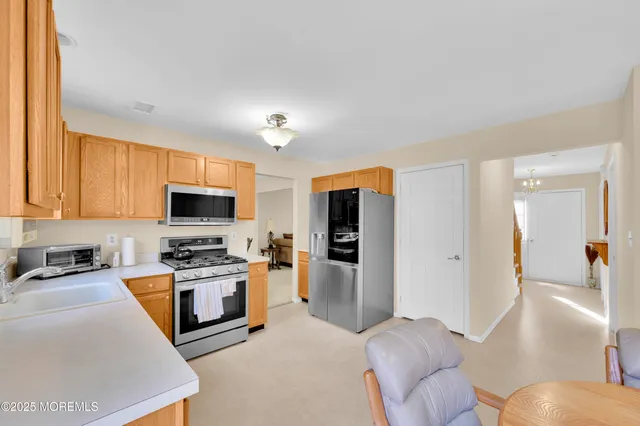 a large white kitchen with stainless steel appliances granite countertop a stove and a sink