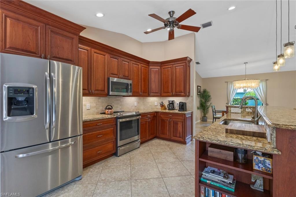 6060 Painted Leaf Lane Naples, FL 34116 - Photo 12 of 49 a kitchen with stainless steel appliances granite countertop a refrigerator stove microwave and sink