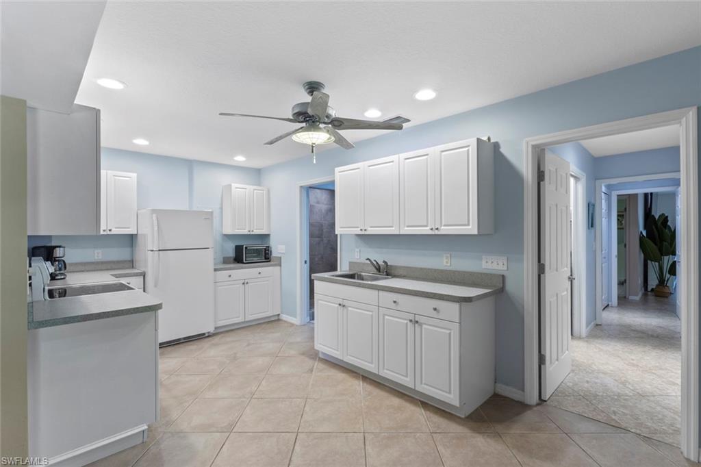 6060 Painted Leaf Lane Naples, FL 34116 - Photo 30 of 49 a kitchen with white cabinets and stainless steel appliances