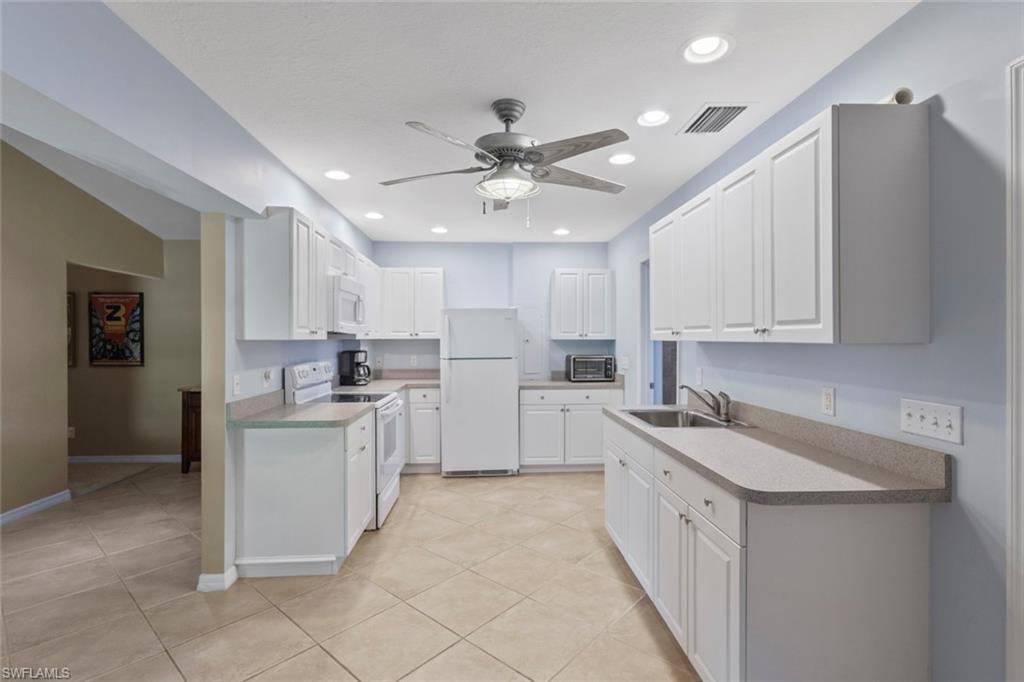 6060 Painted Leaf Lane Naples, FL 34116 - Photo 31 of 49 a kitchen with white cabinets and white appliances