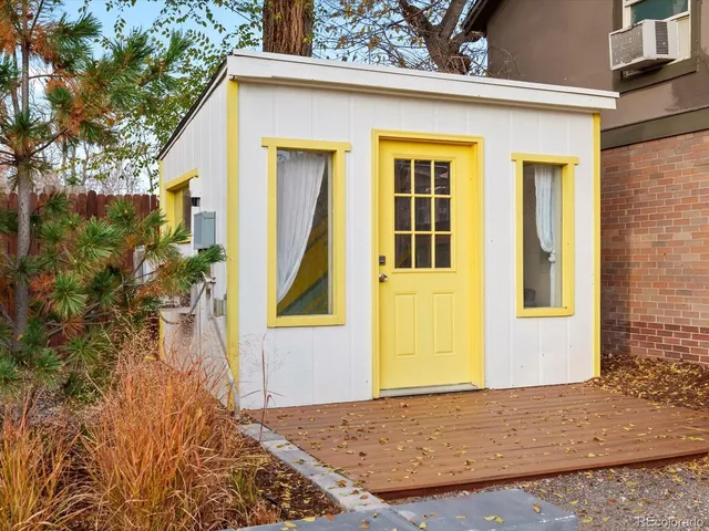 a view of a white house with a small yard and large tree