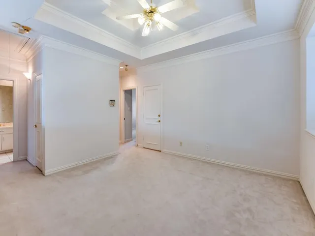 an empty room with a chandelier fan and windows
