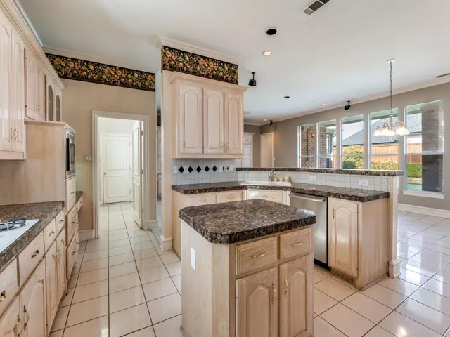a kitchen with granite countertop a stove a sink and a refrigerator