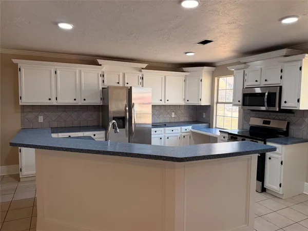 a kitchen with stainless steel appliances granite countertop a sink a stove a refrigerator a microwave a sink and white cabinets