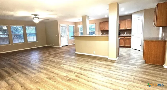 a view of a kitchen with kitchen island granite countertop wooden floor and stainless steel appliances