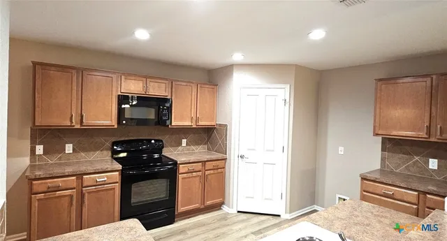 a kitchen with stainless steel appliances granite countertop a stove a sink and a microwave