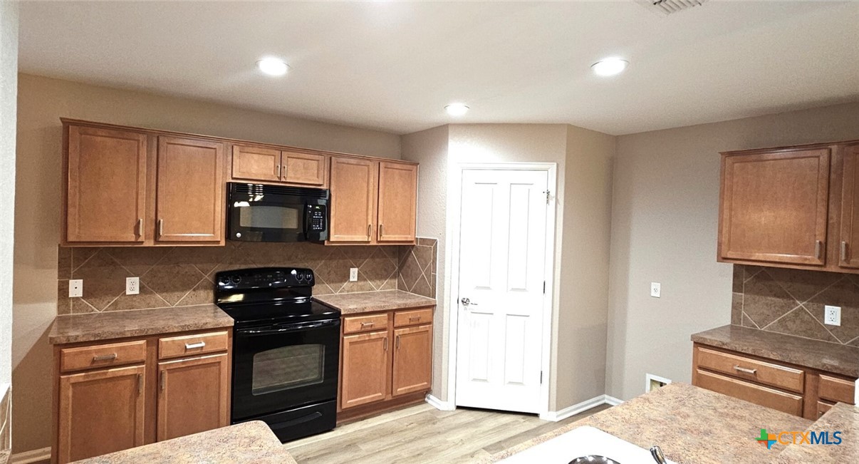 6046 Mule Deer Schertz, TX 78108 - Photo 6 of 19 a kitchen with stainless steel appliances granite countertop a stove a sink and a microwave