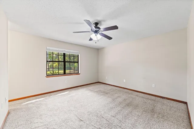 an empty room with windows and fan