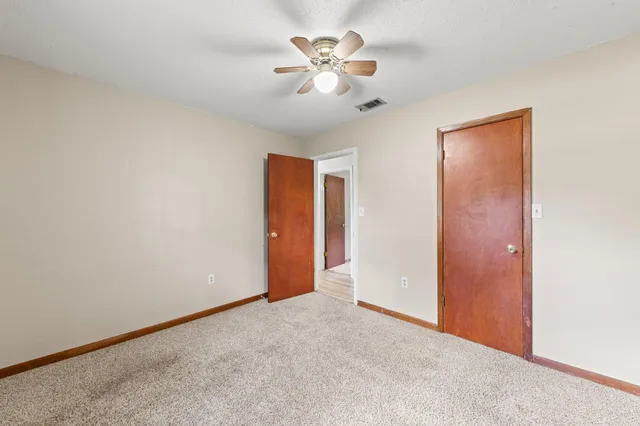an empty room with closet and a chandelier fan