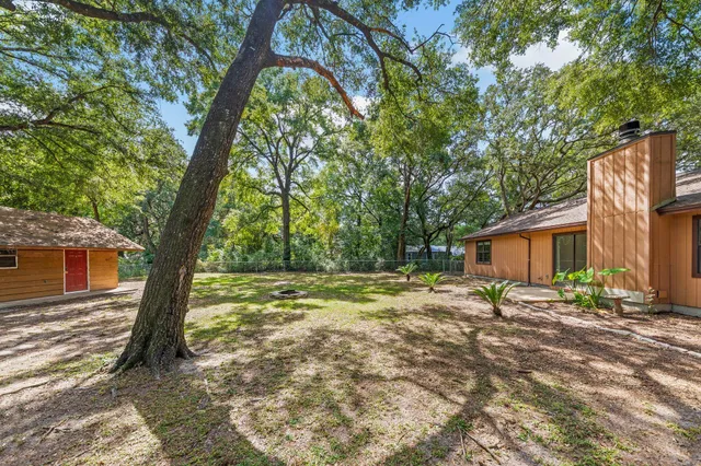 a backyard of a house with trees and outdoor seating