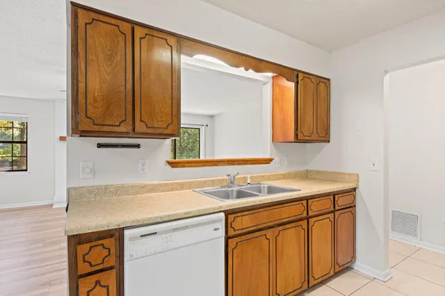 a utility room with stainless steel appliances granite countertop a sink and a window