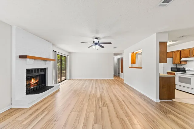 a view of empty room with wooden floor fireplace and a window