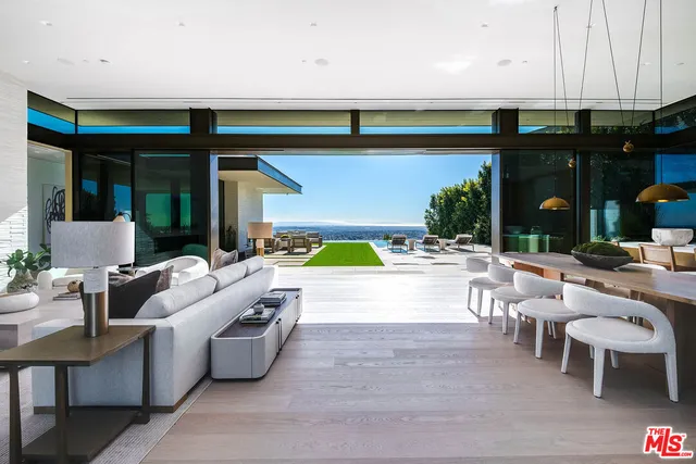 a living room with couches a table and chairs with potted plants