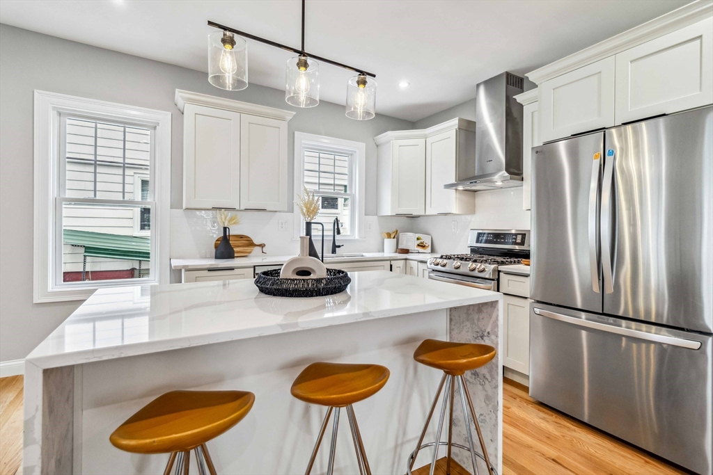 16 Alston Street, Unit 16 Somerville, MA 02143 - Photo 11 of 39 a kitchen with stainless steel appliances a stove a refrigerator and wooden floors
