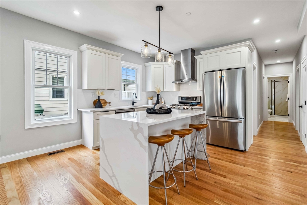 16 Alston Street, Unit 16 Somerville, MA 02143 - Photo 12 of 39 a kitchen with stainless steel appliances granite countertop a refrigerator a stove a sink dishwasher and white cabinets with wooden floor