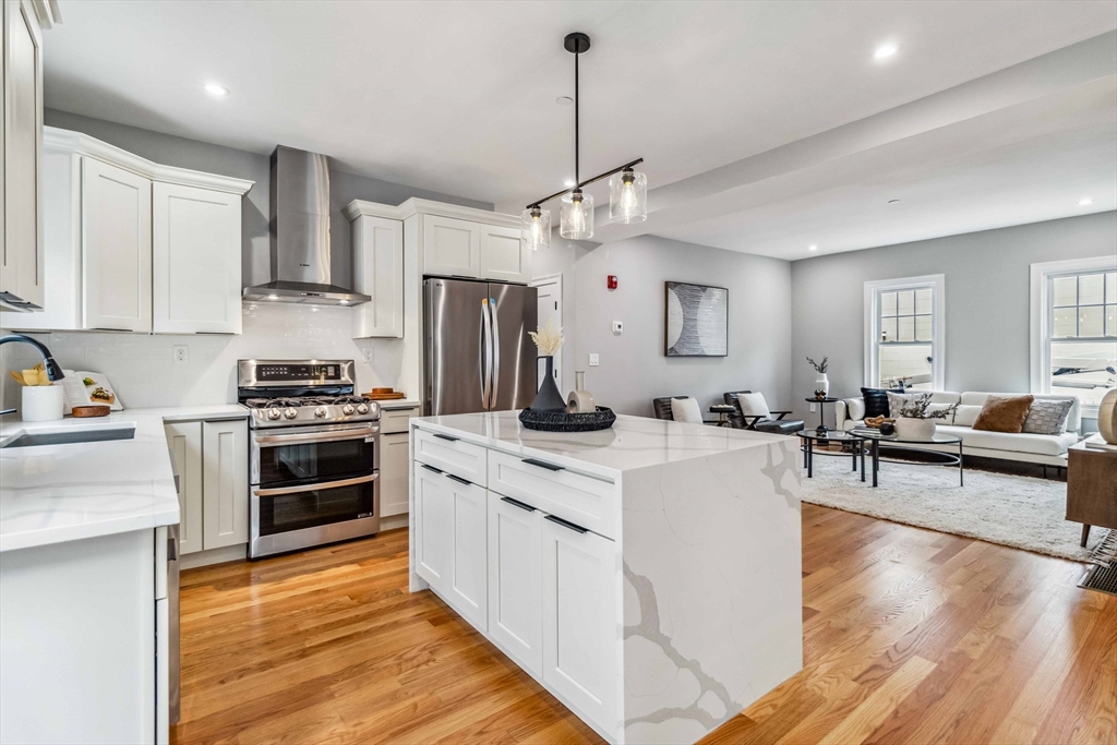 16 Alston Street, Unit 16 Somerville, MA 02143 - Photo 6 of 39 a kitchen with stainless steel appliances kitchen island granite countertop a stove refrigerator and cabinets