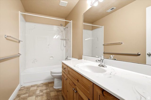 1089 West 2325th Street North Layton, UT 84041 - Photo 25 of 40 Bathroom featuring a white bathtub and shower surround, a wood-finish vanity with a white countertop and integrated sink, a chrome faucet, and patterned floor tile