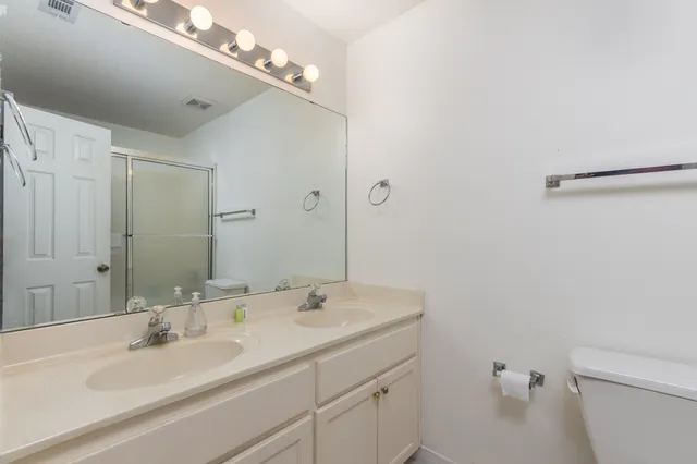 a bathroom with a sink a toilet and a large mirror