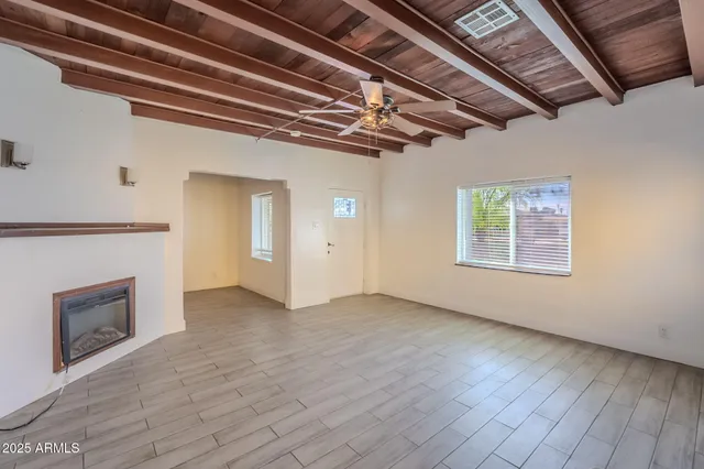 a view of an empty room with wooden floor and a fireplace