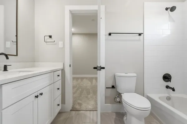 an empty room with wooden floor and kitchen view
