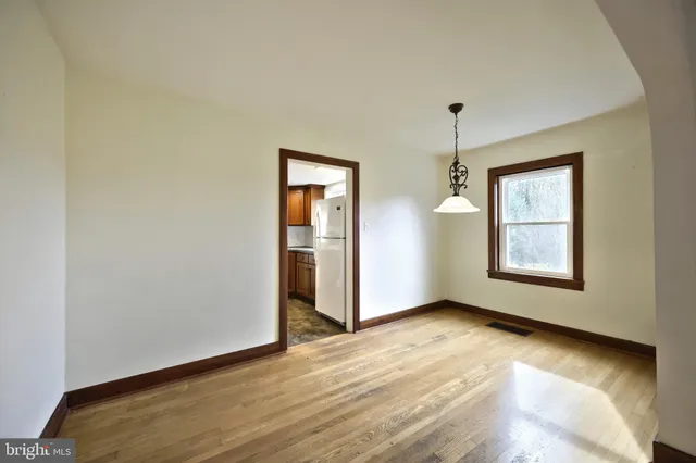a view of a hallway with wooden floor and a bathroom