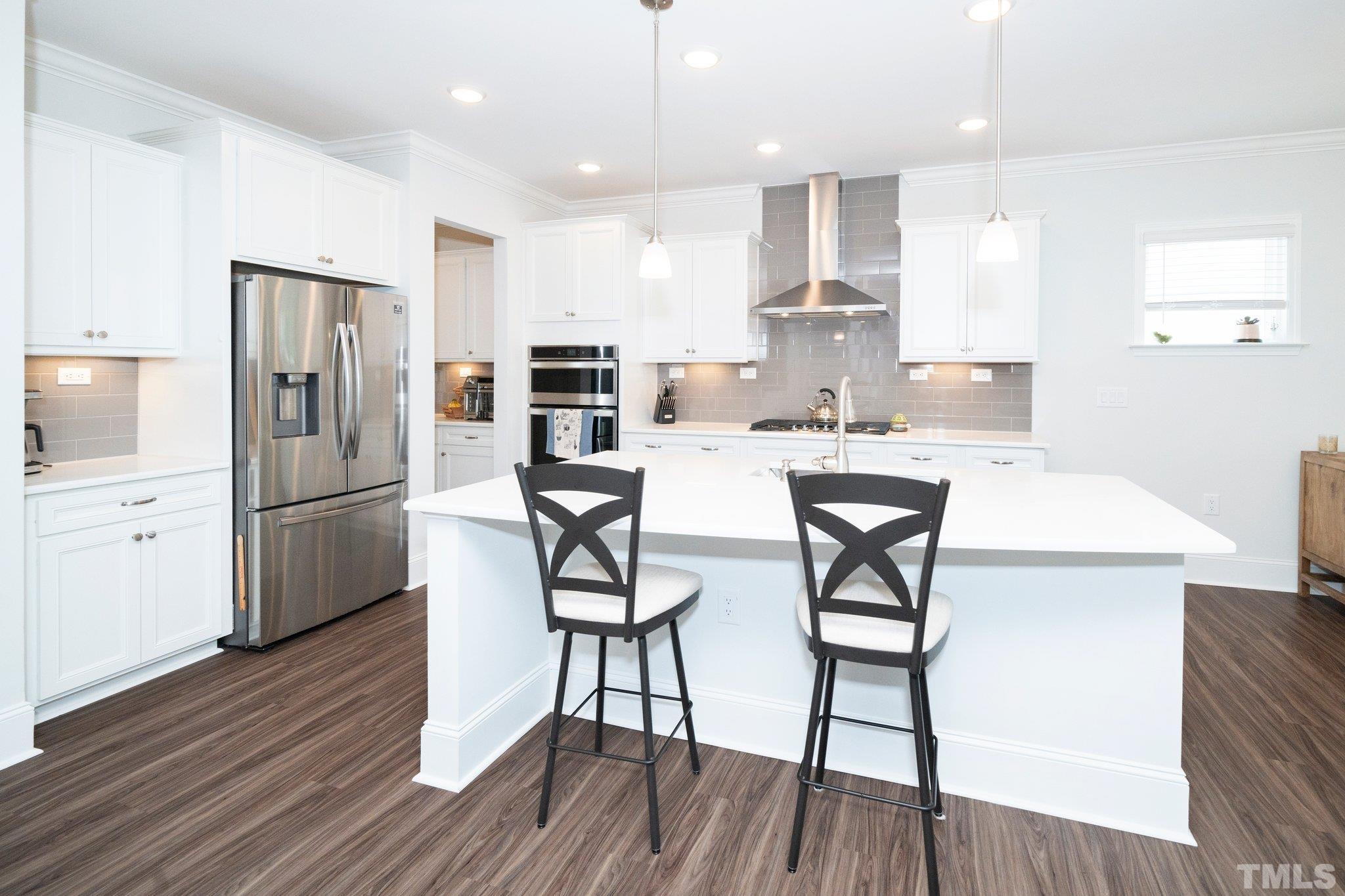 3271 Ripley River Road New Hill, NC 27562 - Photo 13 of 48 a kitchen with stainless steel appliances a dining table chairs microwave and refrigerator