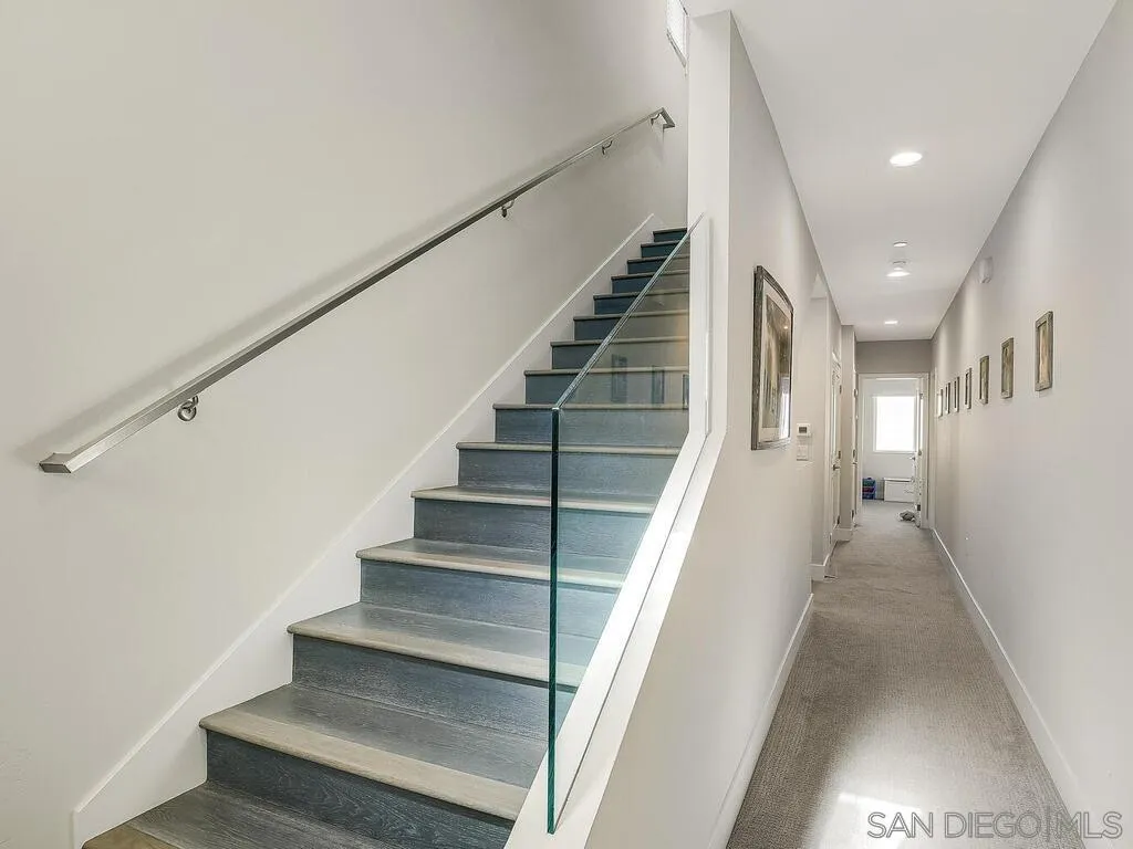 938 Opal Street San Diego, CA 92109 - Photo 23 of 70 a view of staircase with lots of frames on wall and wooden floor