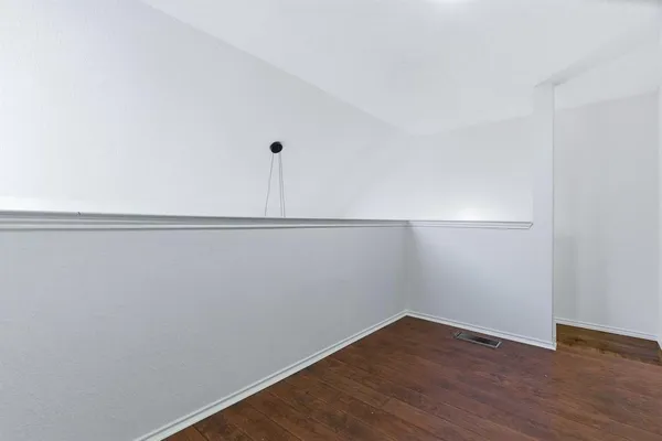 an empty room with wooden floor and ceiling fan