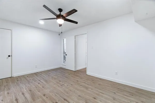 an empty room with wooden floor ceiling fan and windows