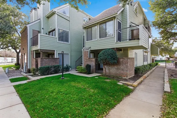 a view of a brick house with a yard and large tree