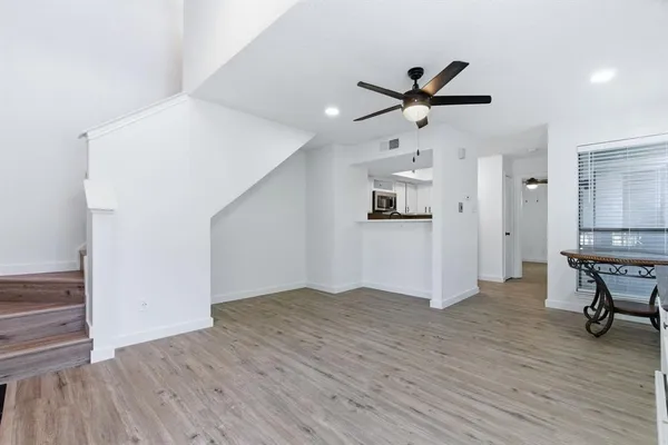 a view of empty room with wooden floor and ceiling fan