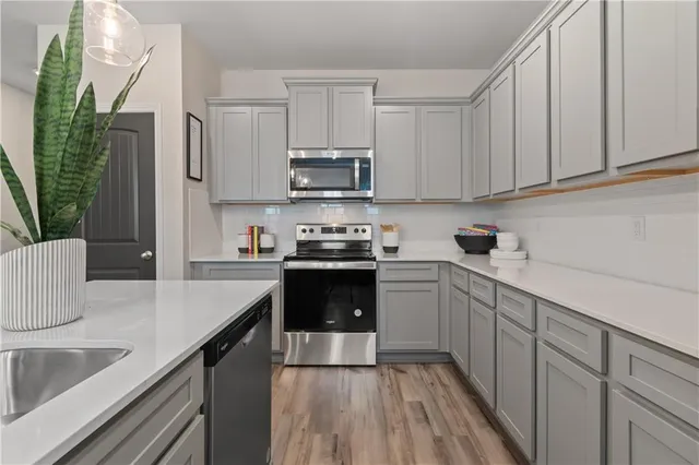 a kitchen with stainless steel appliances granite countertop a refrigerator a sink dishwasher a stove and white countertops with cabinets