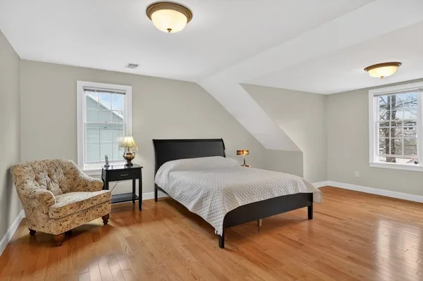 a bedroom with a bed couch and wooden floor