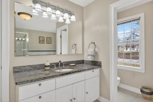 a bathroom with a granite countertop sink a toilet and a mirror