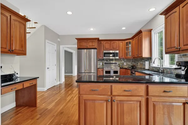 a kitchen with stainless steel appliances granite countertop a sink a stove a refrigerator cabinets and wooden floor