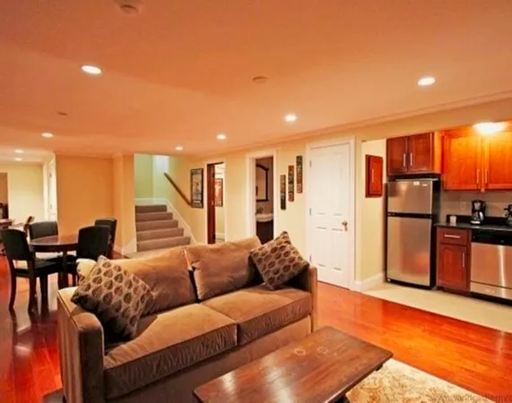 a living room with furniture kitchen view and a wooden floor