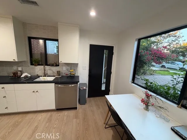 a kitchen with stainless steel appliances white cabinets sink and wooden floor