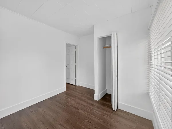 an empty room with wooden floor and window