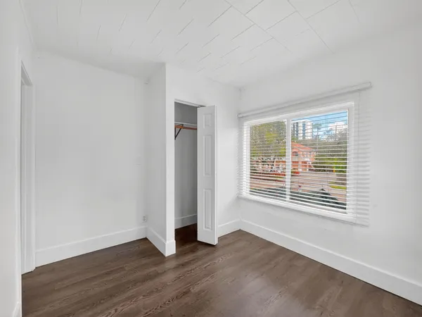 a view of an empty room with wooden floor and a window