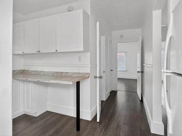 a kitchen with white cabinets and wooden floor