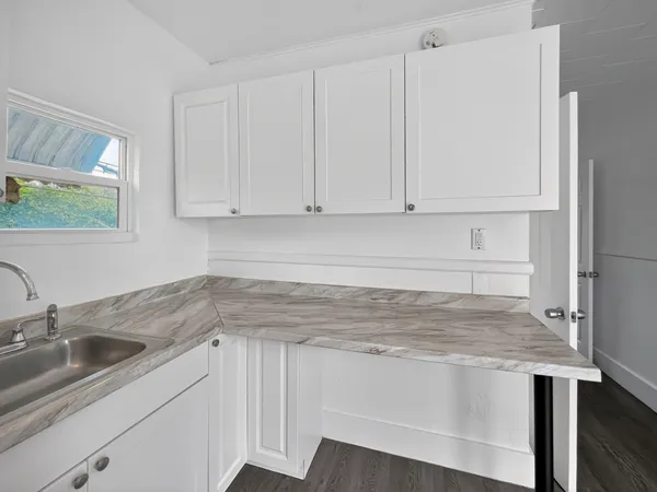 a kitchen with granite countertop white cabinets and sink